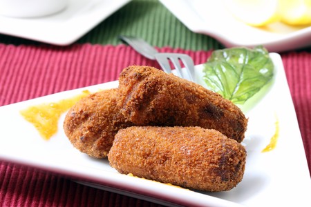 chicken fried croquettes on white platter with basil leaf