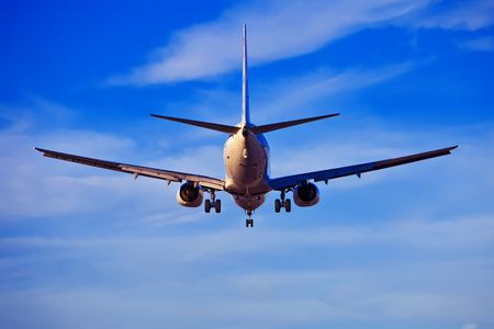 rear view of an airplane landing with blue sky backgroundの写真素材