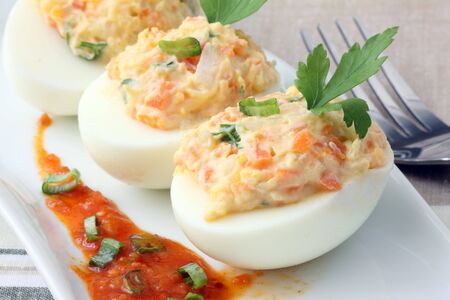 boiled egg filled with potato salad and tomato sauceの写真素材