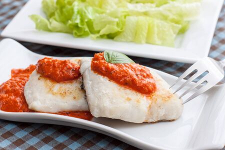 hake fillet with pepper sauce on white trayの写真素材