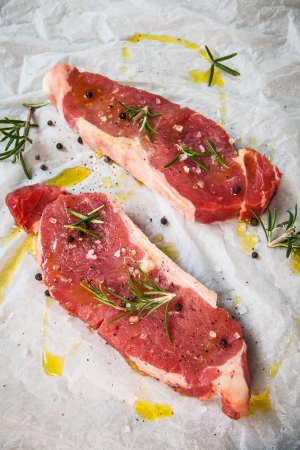 two fresh and raw beef steak seasoning with olive oil and herbsの写真素材