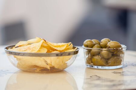 potato chips and olives on a glass bowlの写真素材