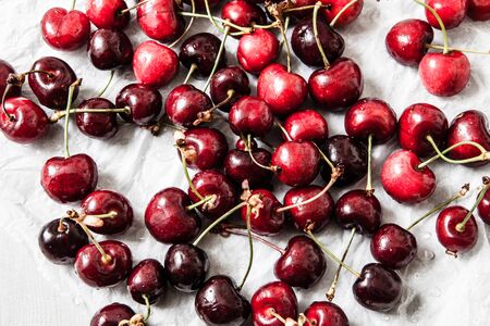 fresh sour cherries in paper with water drops on grey wooden tableの写真素材