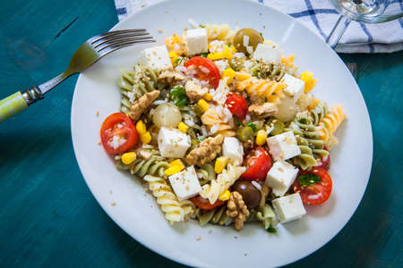 pasta salad with tomato rice and feta cheese on white plateの写真素材