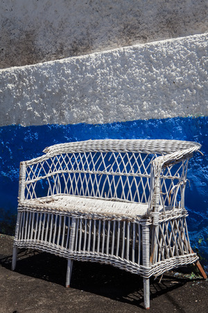 old wicker chair on white color in blue wallの写真素材