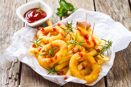 french fries with calamari and rosemary on white paperの写真素材