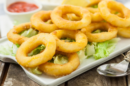 deep fried calamari with lemon and salad on white trayの写真素材