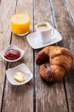 continental breakfast with orange juice and black coffee on wooden table