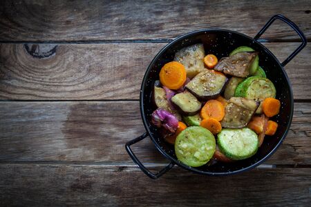 roasted vegetables on pot isolated on wooden tableの写真素材