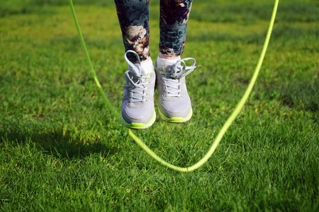 woman jumping on a skipping rope in a park close-up.の写真素材