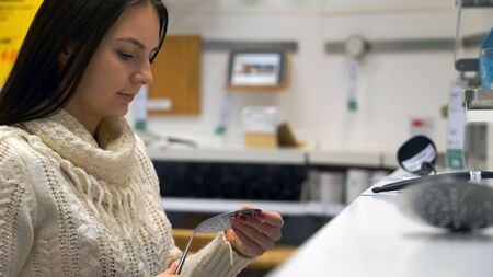 woman chooses kitchen ladles in shop.