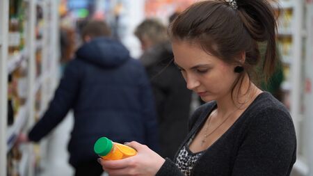 woman buys juice in supermarket or store.