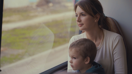 Young mother and little son ride on a bus through city during sunny dayの写真素材