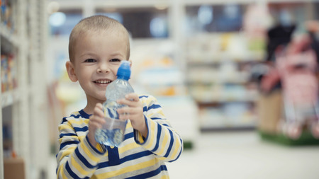 Little boy in the supermarket choose a bottle of mineral water.の写真素材