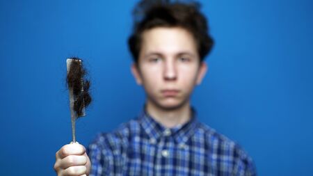 Balding problem men. Teen hand holding loss hair combの写真素材