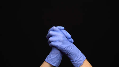 Medical hands with blue gloves clapping on black backgroundの写真素材