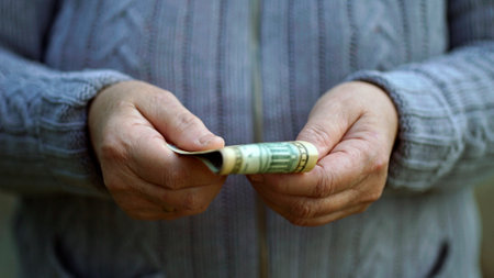 Elderly woman holds cash in armsの写真素材