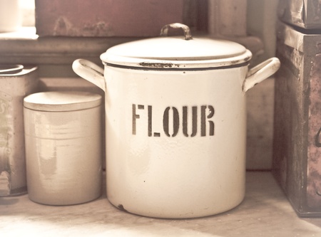 Vintage toned image of an enamel flour tin in an old style kitchenの写真素材