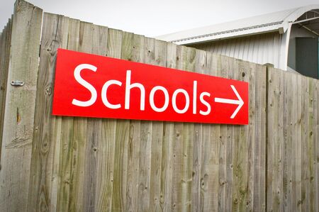 A vibrant red school sign on a wooden fenceの写真素材