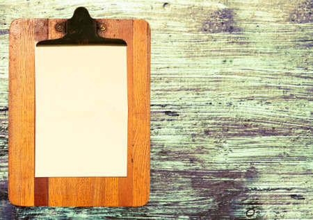A wooden antique clipboard with blank paper on a wooden surfaceの写真素材