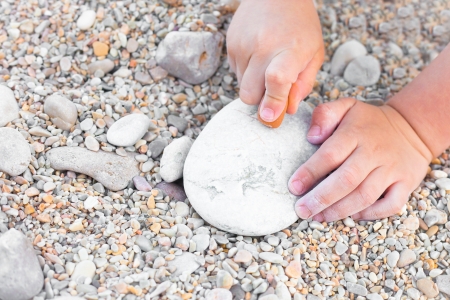 Close up of a young child's hands drawing on a stoneの写真素材