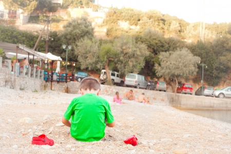 A four year old boy sitting on a pebble beachの写真素材