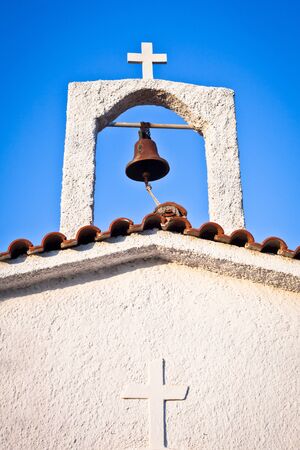Bell and cross on a whitewashed greek churchの写真素材