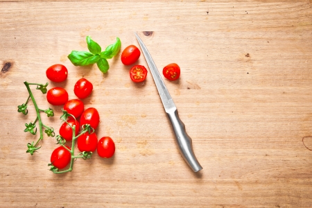 Fresh cherry tomatoes and basil on a chopping boardの写真素材