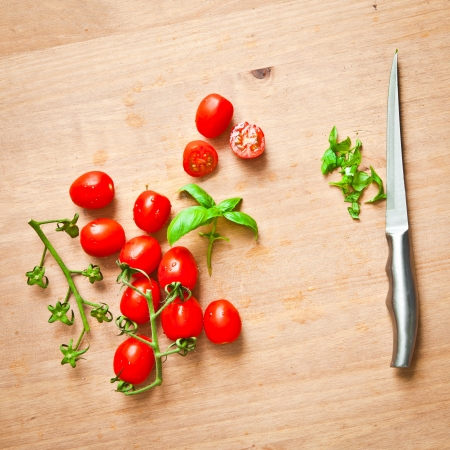 Fresh cherry tomatoes and basil on a chopping boardの写真素材