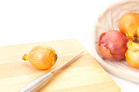 Onions ready for chopping with a metal knife, white backgroundの写真素材