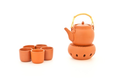 A terracotta teapot on a candle heater on white background with cupsの写真素材
