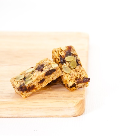 Pumpkin seed and raisin flapjack on a wooden chopping board, white backgroundの写真素材