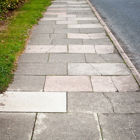 Details of a sidewalk between a road and a green grass vergeの写真素材