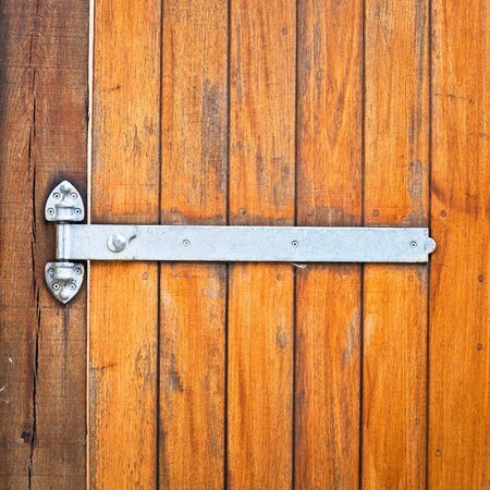 A modern metal hinge on a wooden doorの写真素材
