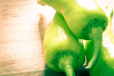 Three green peppers on a wooden surfaceの写真素材