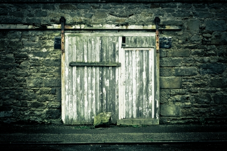 Old weathered wooden door in a wall in muted tonesの写真素材