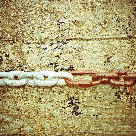 Linked metal chains on a stone wallの写真素材