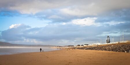 Walkers and joggers on Aberafan beach in Wales in Decemberの写真素材