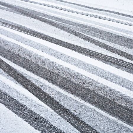 Many tyre trackson a road  in the snowの写真素材
