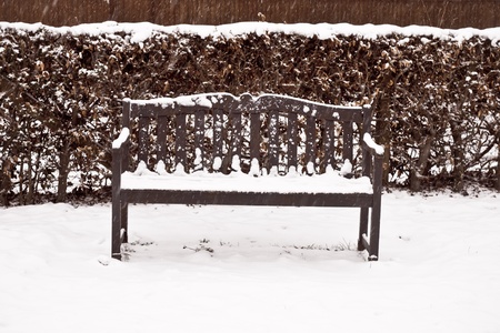 A wooden bench in a garden in the snowの写真素材