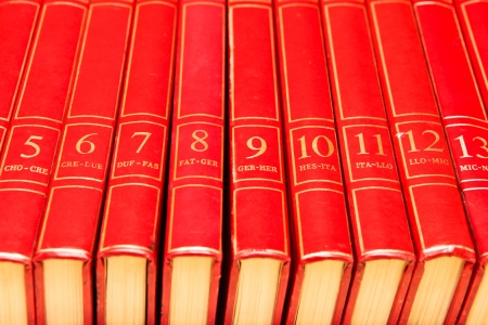 Row of red encyclopedia books on a shelfの写真素材