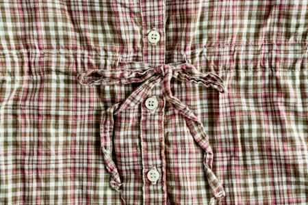 Close up of a woman's top with buttons and a tie ribbon
