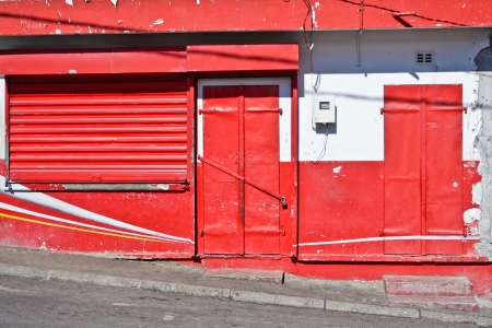 Colorful red door and shutter on a closed storeの写真素材