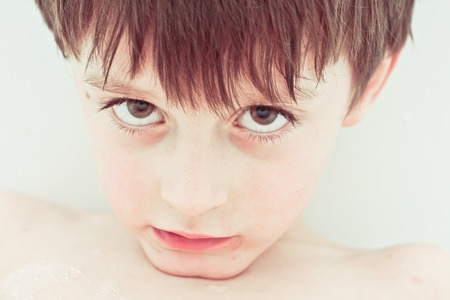 Close up of the face of a six year old boy with a sad expressionの写真素材