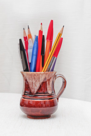 Pens and pencils in a mug on a a deskの写真素材