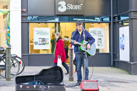 NORWICH, UK - FEBRUARY 21, 2014: A young male busker performs in a street in the city centre of...