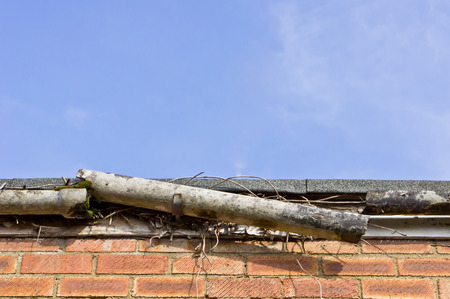 A broken plastic gutter on the roof of a houseの写真素材