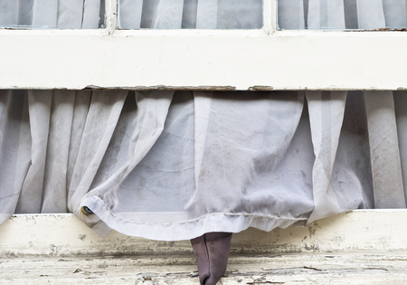A dirty net curtain hanging out of an open windowの写真素材