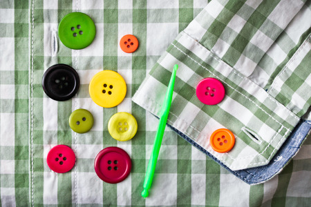 Colorful plastic buttons on a checked shirt as a background imageの写真素材