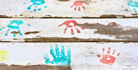 Hand prints in red and blue paint on a white wooden surfaceの写真素材